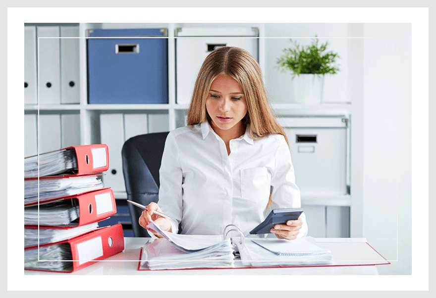 A woman sitting at her desk with papers and cell phone.