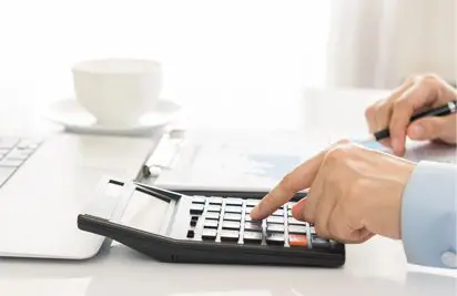 A person using a calculator on top of a desk.