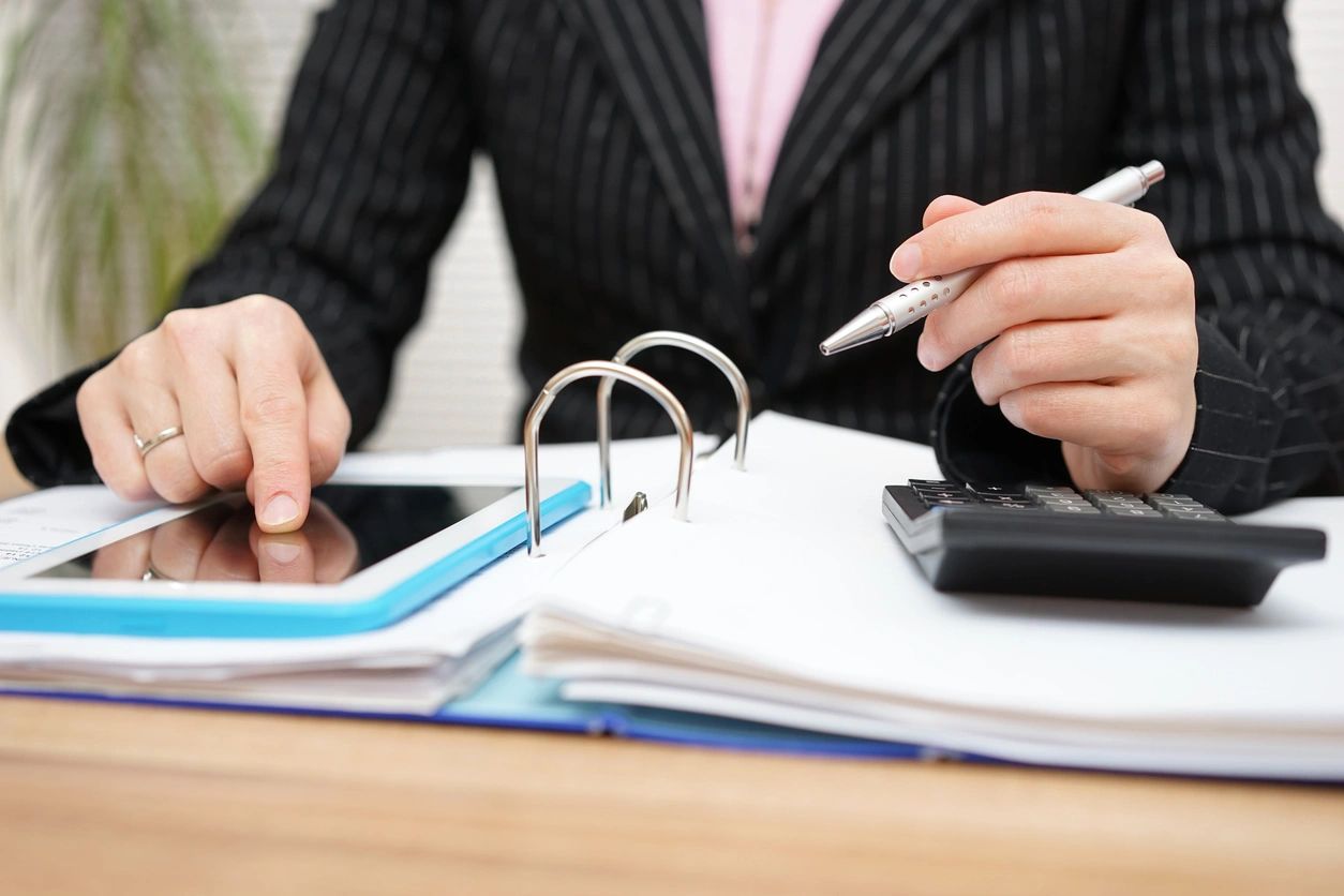 A person sitting at a table with papers and a tablet.